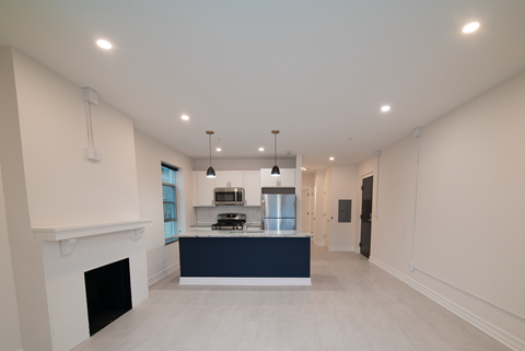 a kitchen and living room with white walls and a black counter top